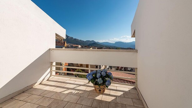 A balcony with a potted plant, a railing, and a view of distant mountains. - Bed & Breakfast Dorgali (Dorgali)