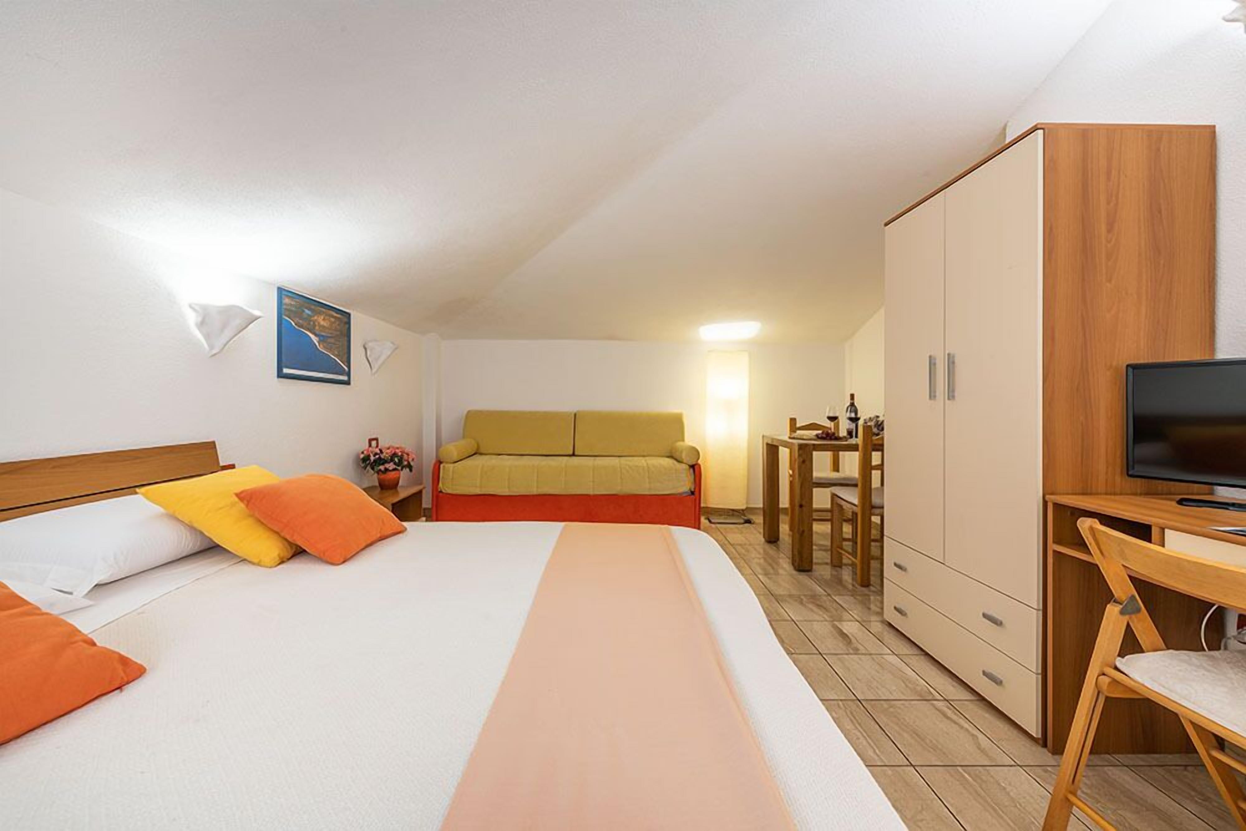 Een hotelkamer met een bed, een bureau, een televisie en een kledingkast.