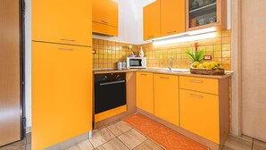 A kitchen with orange cabinets, a microwave, and a sink. - Bed & Breakfast Dorgali (Dorgali)