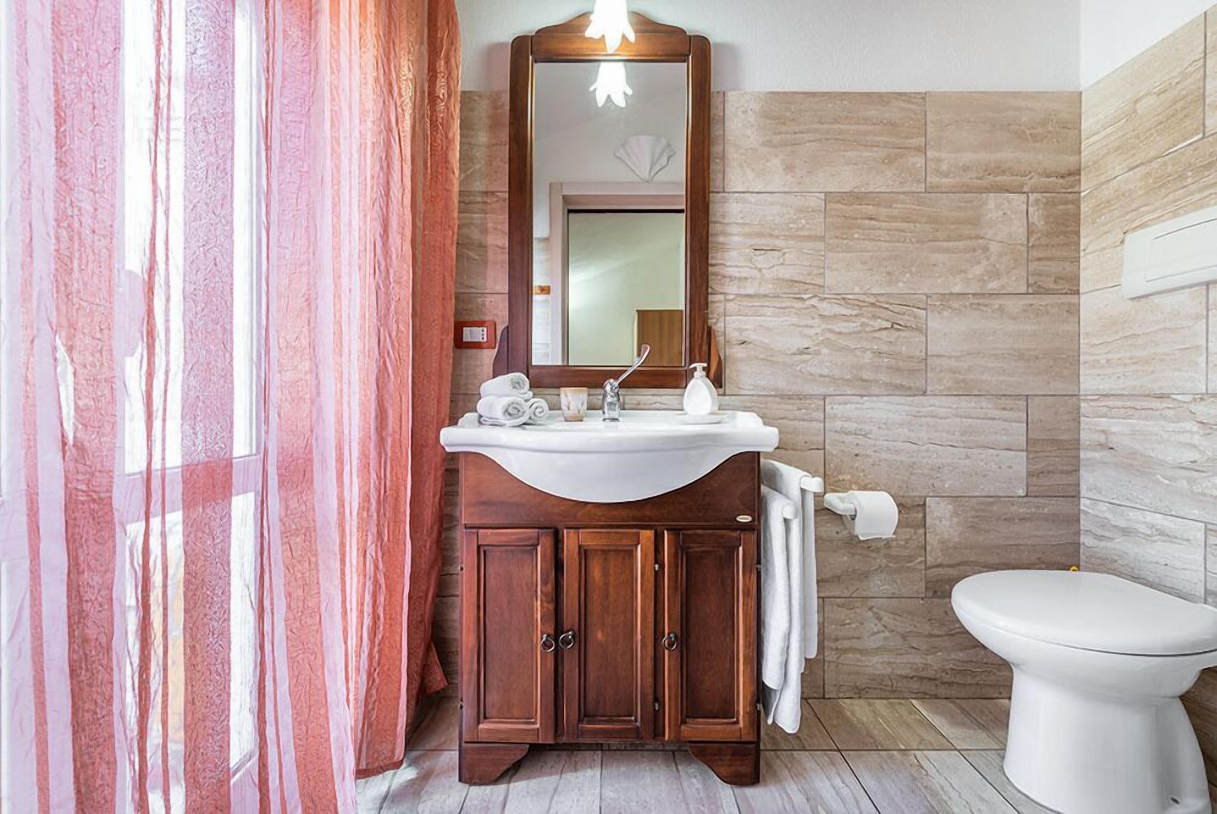 A bathroom with a wooden vanity, white sink, and a large mirror.