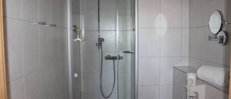 Un baño moderno con ducha envuelta en vidrio, inodoro empotrado y un perchero para toallas.