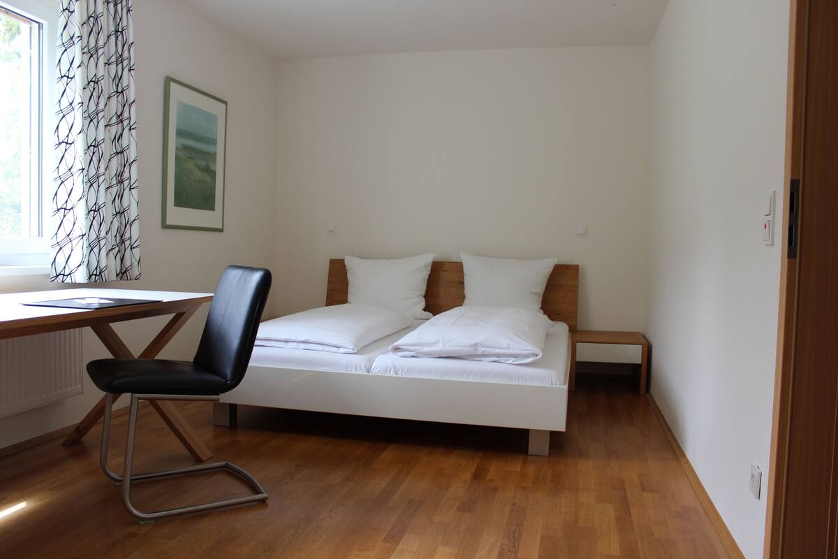 A bedroom with a bed, a desk, and a chair.