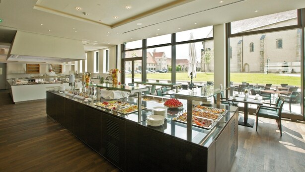 A modern dining area with a buffet setup, large windows, and a view of the building's exterior. - Poststation zum Alten Forstamt (Morschen)