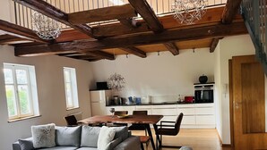A modern living room with a sofa, a coffee table, and a dining area with a table and chairs. - Poststation zum Alten Forstamt (Morschen)