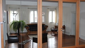 A spacious room with a large sliding glass door, wooden flooring, and a seating area with a sofa and chairs. - Poststation zum Alten Forstamt (Morschen)
