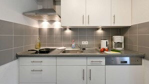A modern kitchen with white cabinets, a stainless steel range hood, and a built-in dishwasher. - Comfortable, modern living in a central, quiet island location for 2 people (Wangerooge)