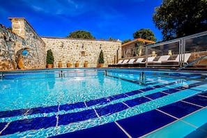 Una piscina al aire libre, sombrillas, sillones reclinables de piscina