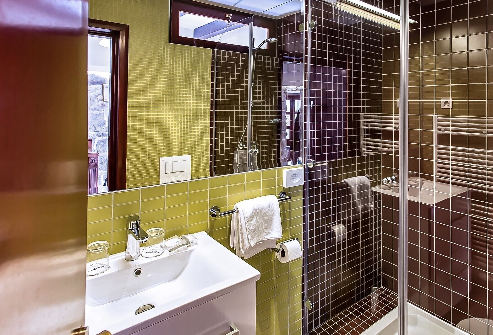 A bathroom with a sink, mirror, and shower area.