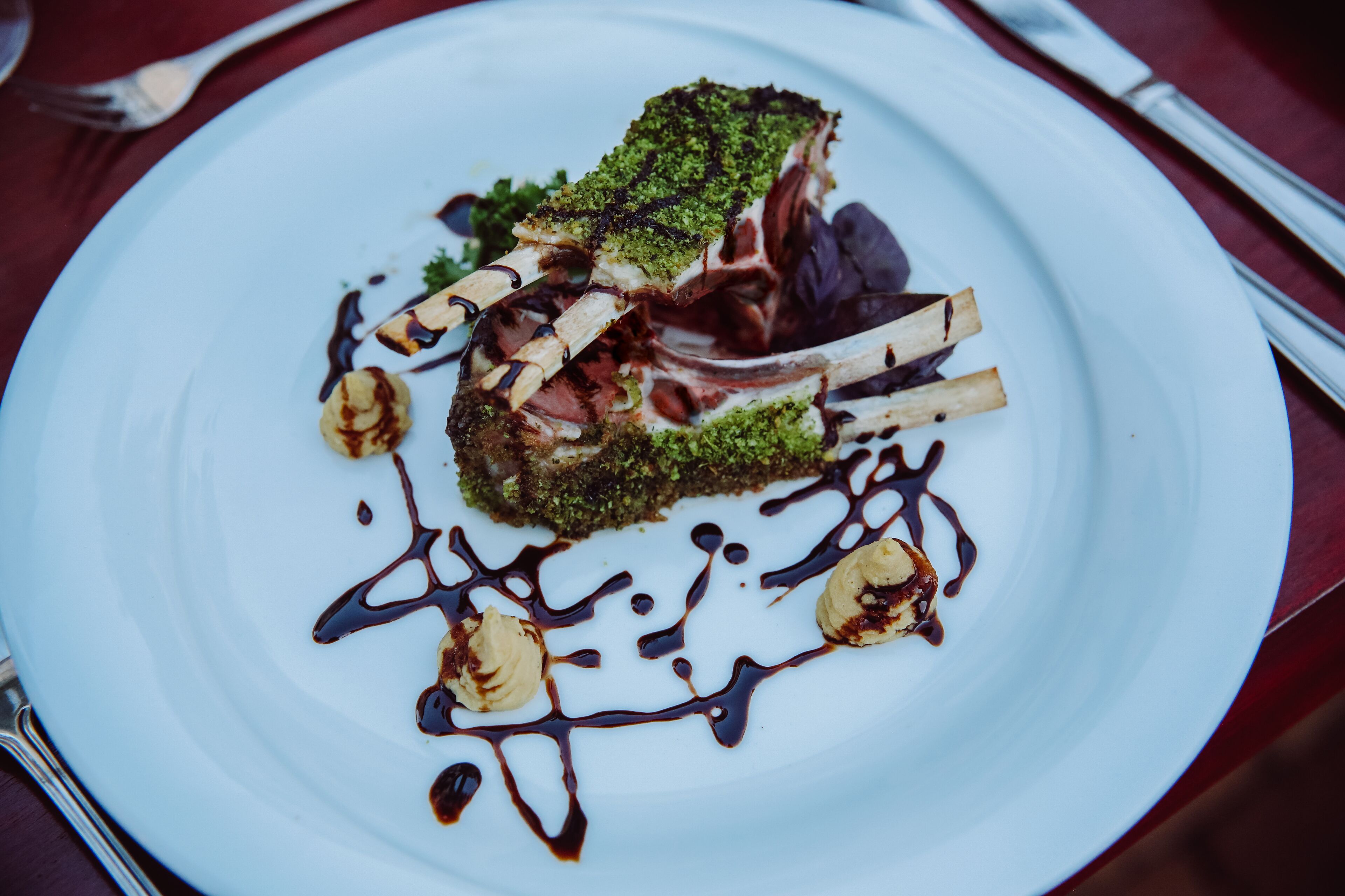 Un plato blanco con un guiso, que incluye un ingrediente con cobertura verde y algo de salsa.