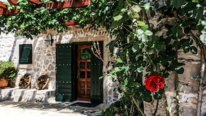 A stone building with a wooden door and a red rose in a pot. - Heritage Hotel Raznjevica Dvori (Polaca)