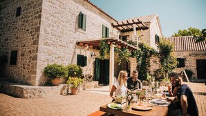 An outdoor dining area with stone buildings, a pergola, and potted plants. - Heritage Hotel Raznjevica Dvori (Polaca)