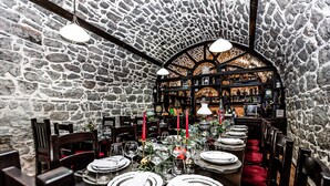 A restaurant with stone walls and a high arched ceiling. Tables are set with white plates, silverware, and red napkins. - Heritage Hotel Raznjevica Dvori (Polaca)