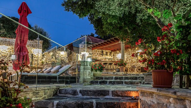 A stone staircase leading to a terrace with a stone wall, potted plants, and a red umbrella. - Heritage Hotel Raznjevica Dvori (Polaca)