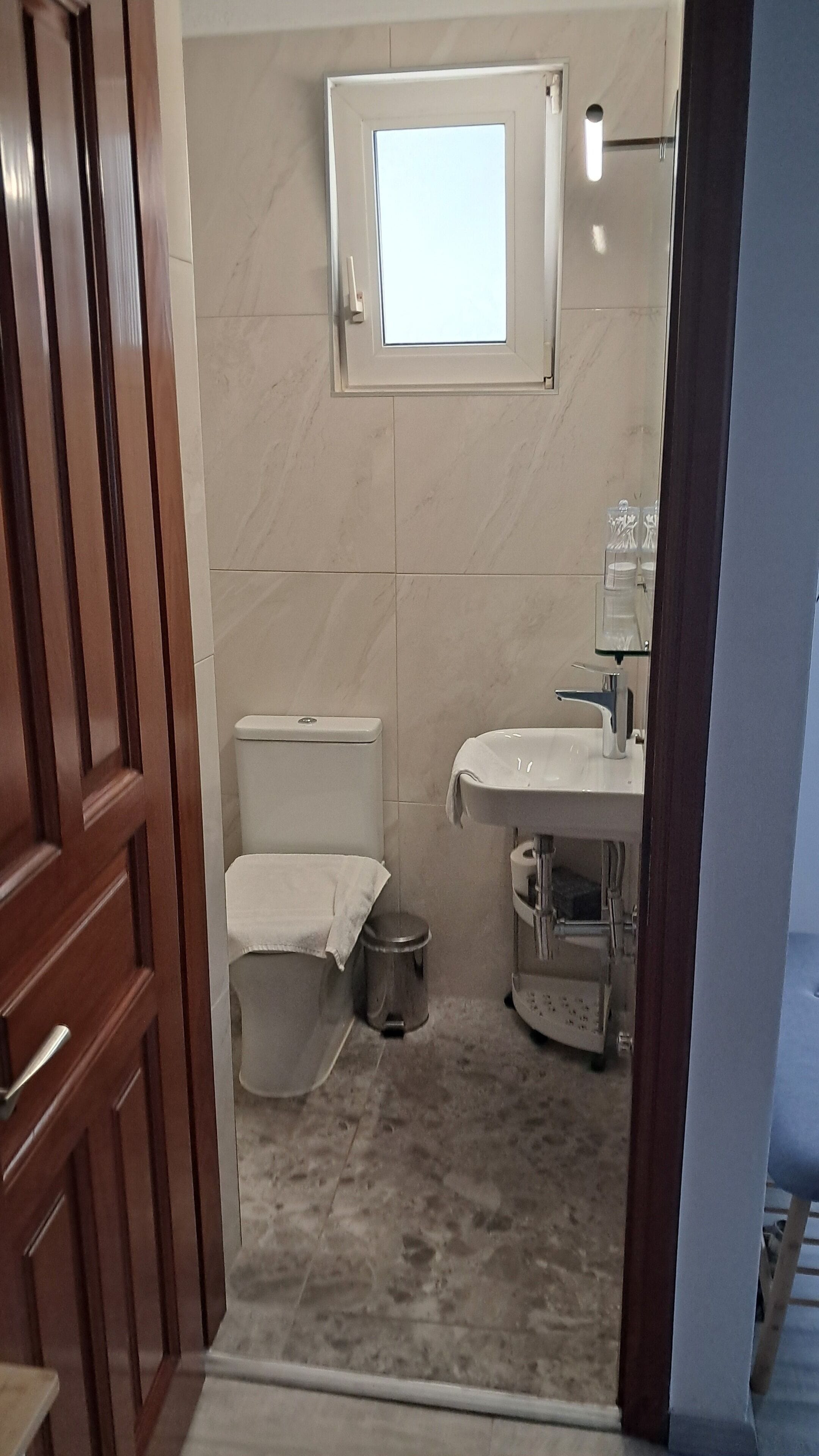 A bathroom with a toilet, sink, and a small window.