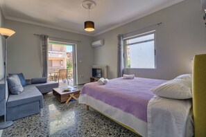 Una habitación de hotel moderna con cama, sofá, televisión y balcón con mesa y sillas.