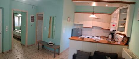 A compact kitchen with a wooden countertop, a bench, and a dining area with a sofa.