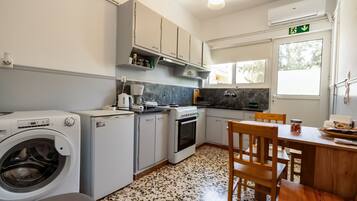 A compact kitchen with a washing machine, a coffee maker, and a dining area with a table and chairs.