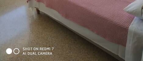 Camera d'albergo con due letti, una piccola scrivania e un balcone con sedie.
