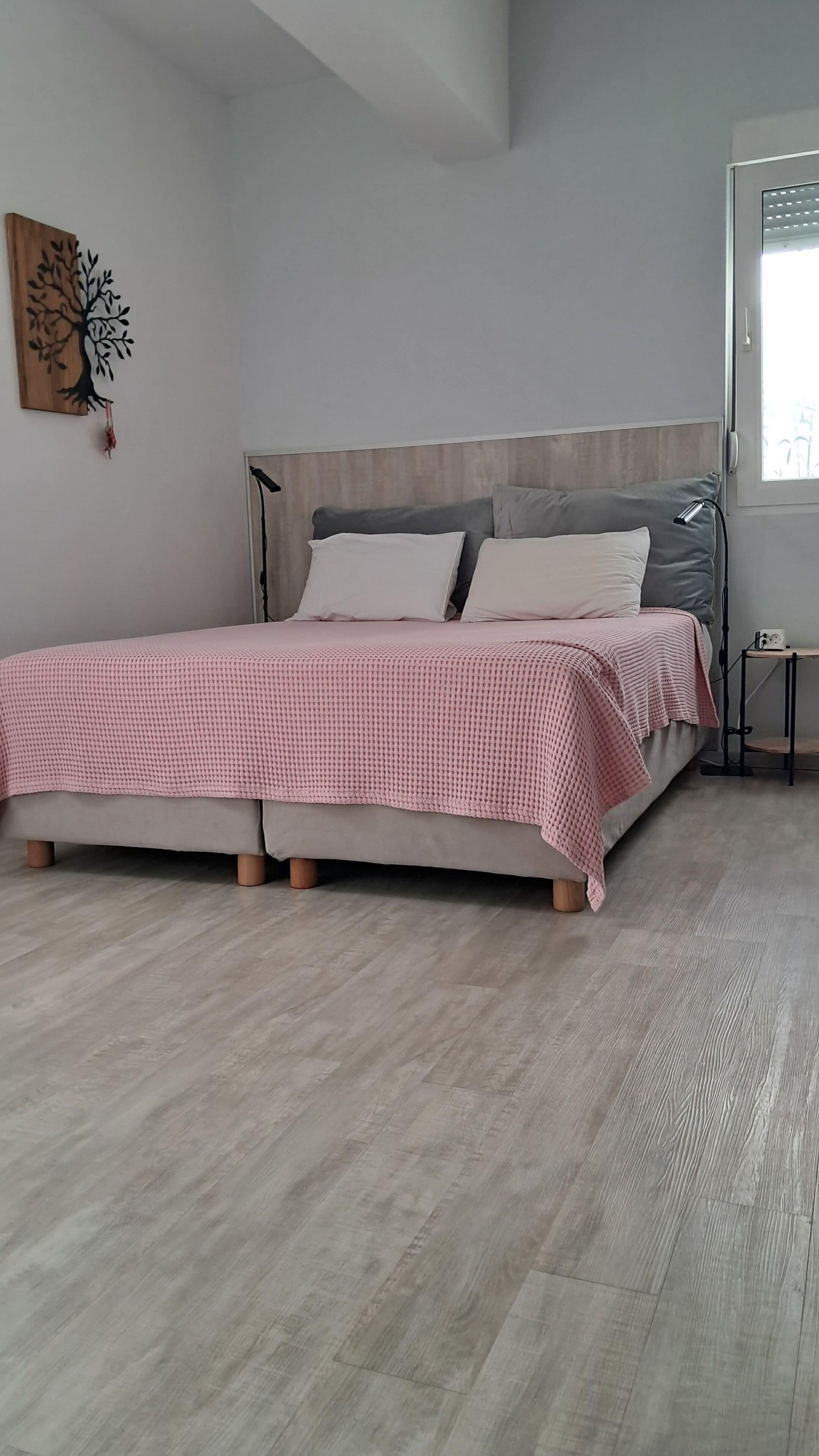 A bedroom with a bed, a bedside table, a lamp, and a window.