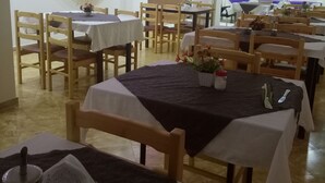 A restaurant with multiple tables and chairs, a TV mounted on the wall, and a ceiling with pink lighting. - Remes hotel (Constantine)