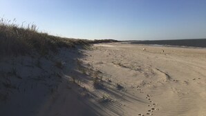 A sandy beach with dunes and footprints leading to the water. - 2 Bed/2 Bath on 1/4 acre w/fenced yard, short walk to 40th thru rolling dunes. (Nantucket)