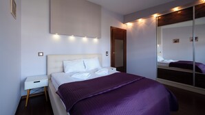 Una habitación de hotel moderna con una cama grande, una mesita de noche, un espejo y un armario.