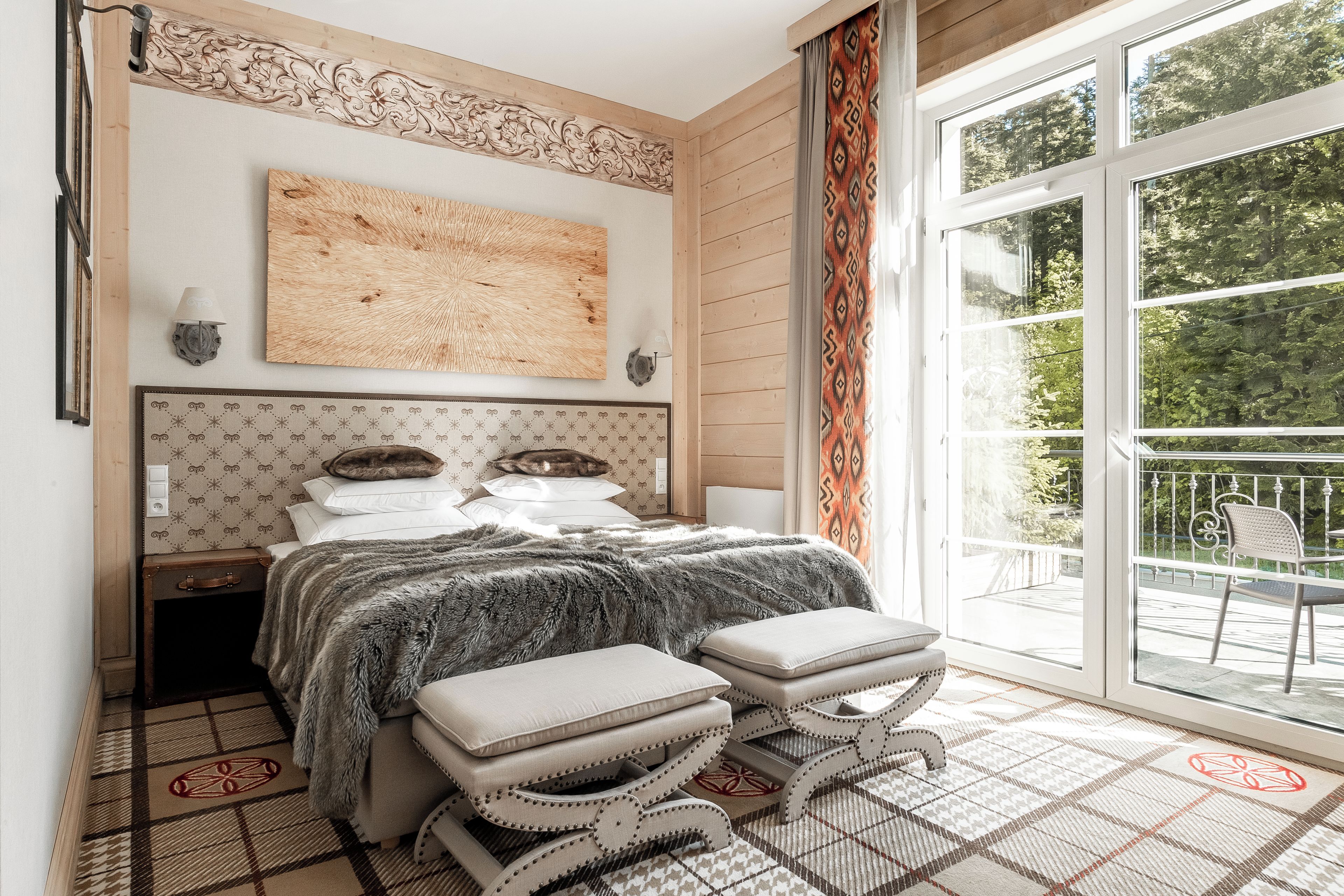 Un dormitorio con una cama grande, vistas al exterior a través de un ventanal corredero y un adorno decorativo sobre la cama.