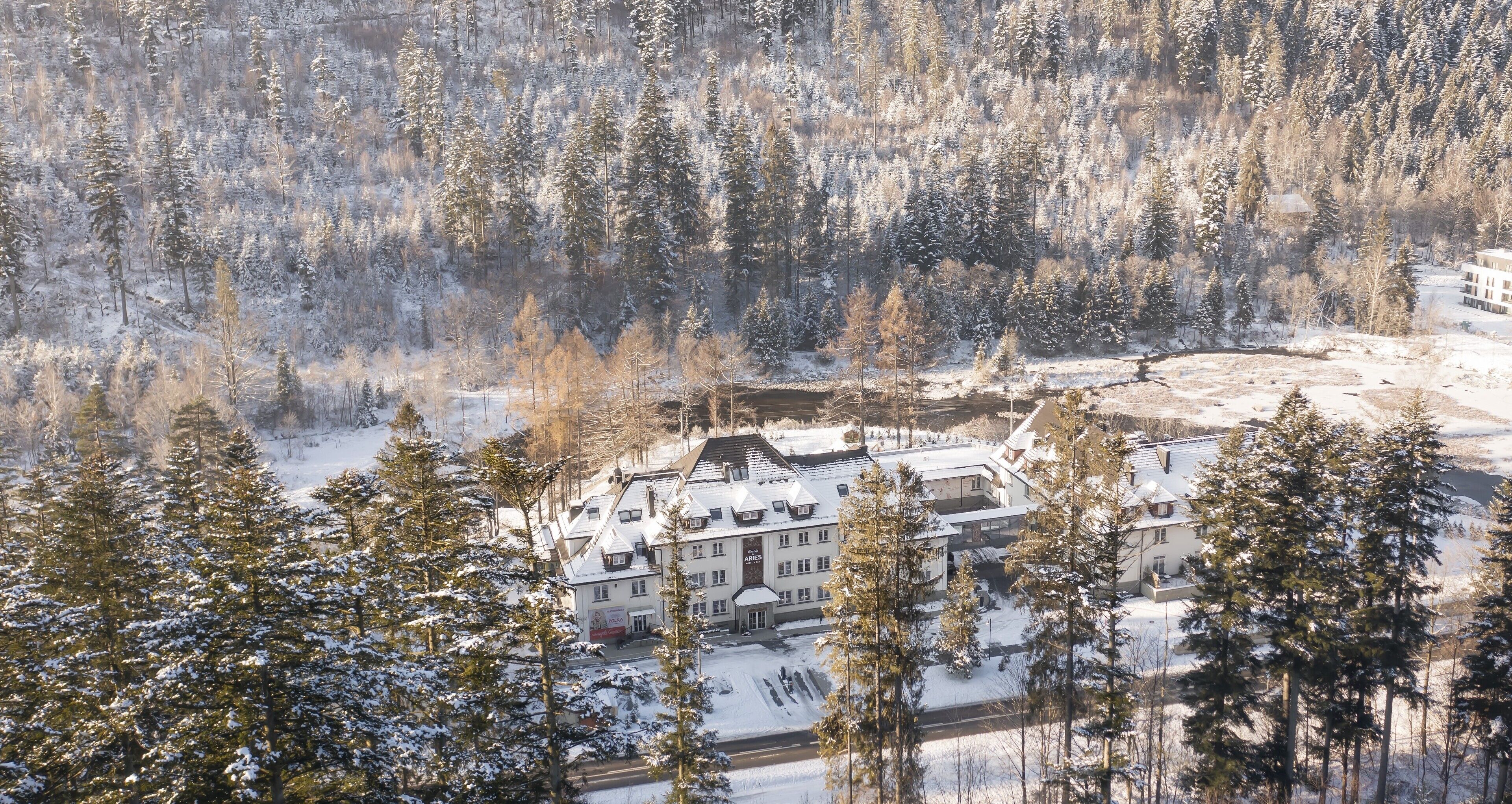 A large, multi-story building surrounded by snow-covered trees.