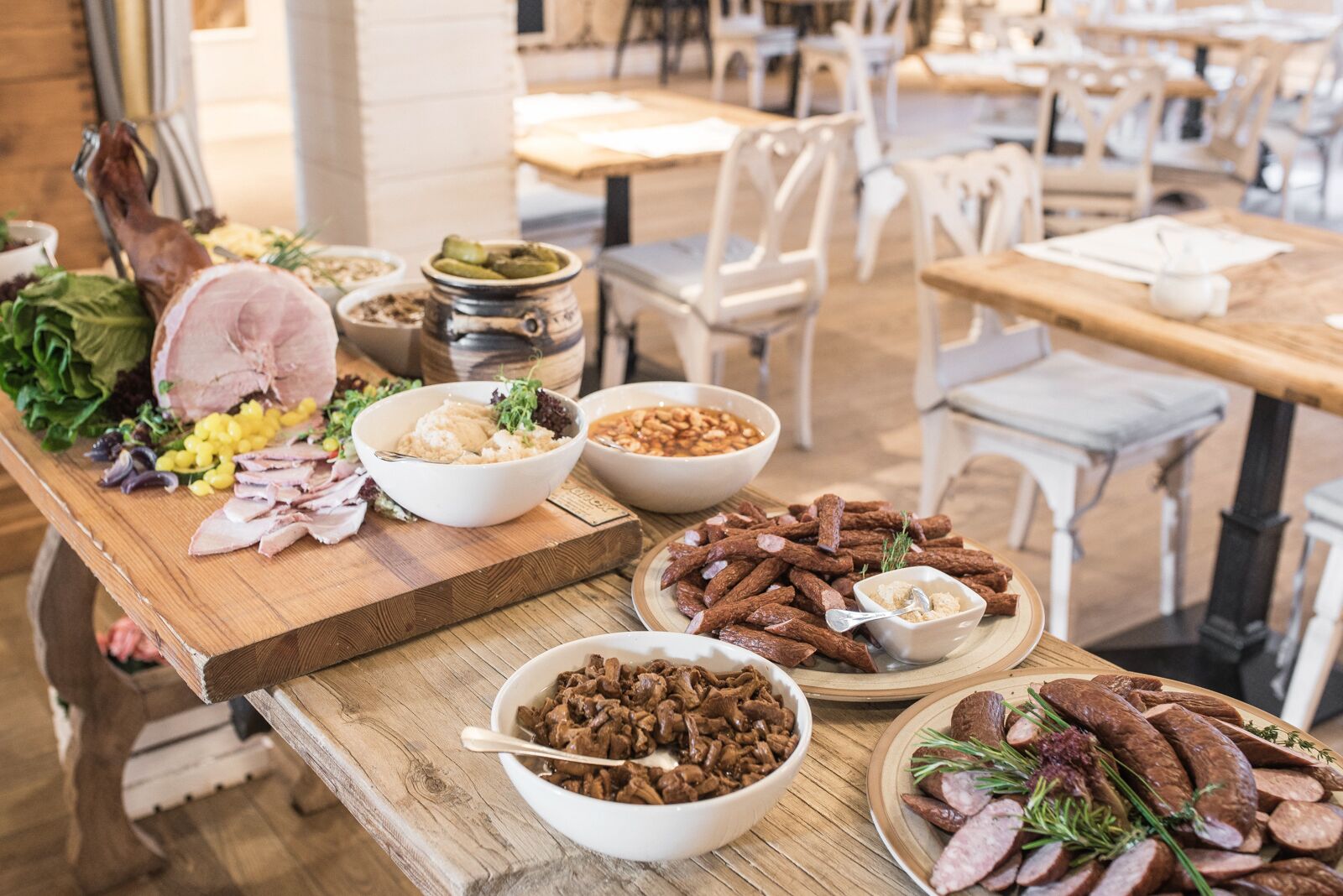 Une table en bois sur laquelle on trouve divers aliments, notamment de la viande tranchée, des légumes et des condiments.