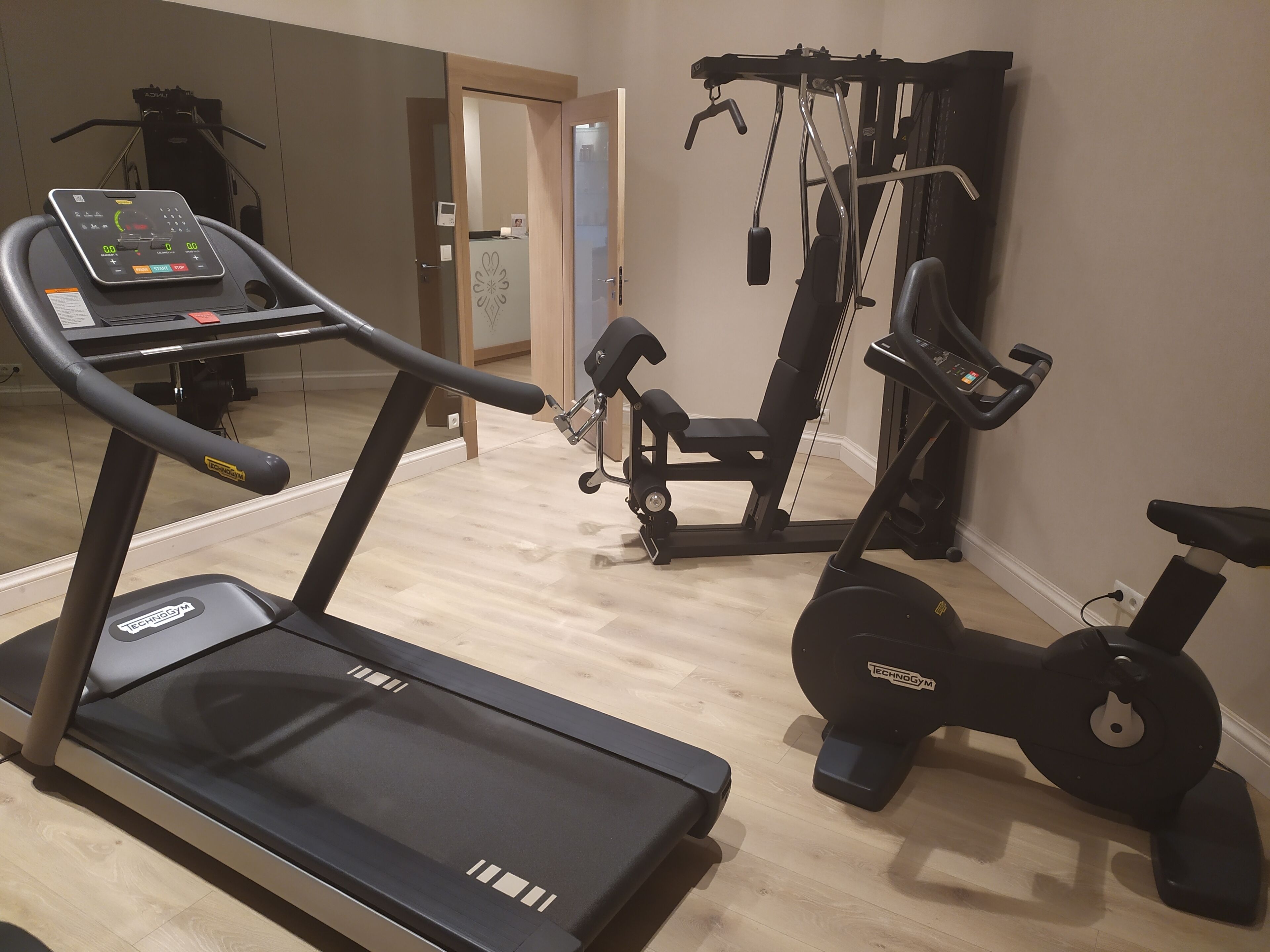 A home gym with a treadmill, elliptical, and weight machine.