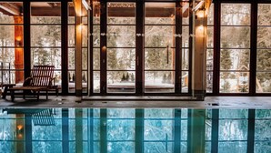 A pool area with a wooden chair and large windows overlooking a snowy landscape. - Aries Hotel & SPA Wisla (Wisla)