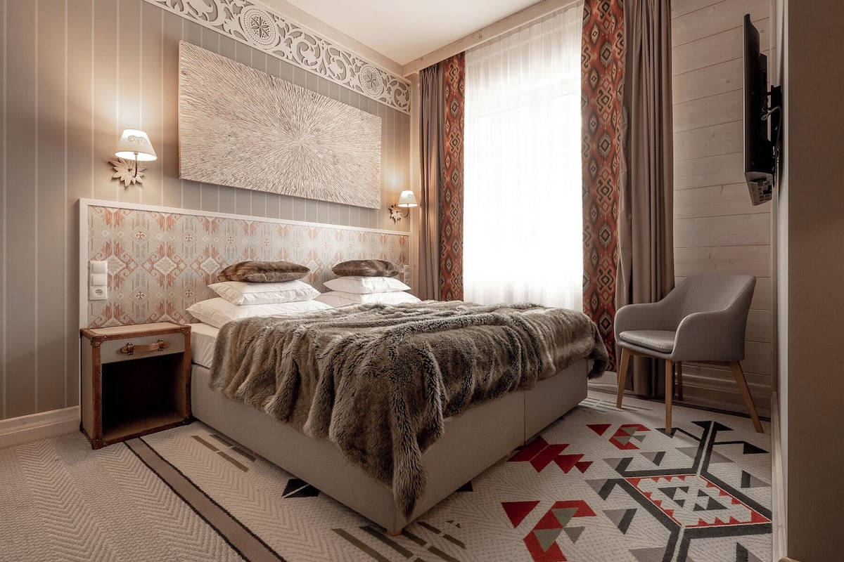 Un dormitorio moderno con una cama grande, una mesita de noche, una silla y un panel decorativo en la pared.