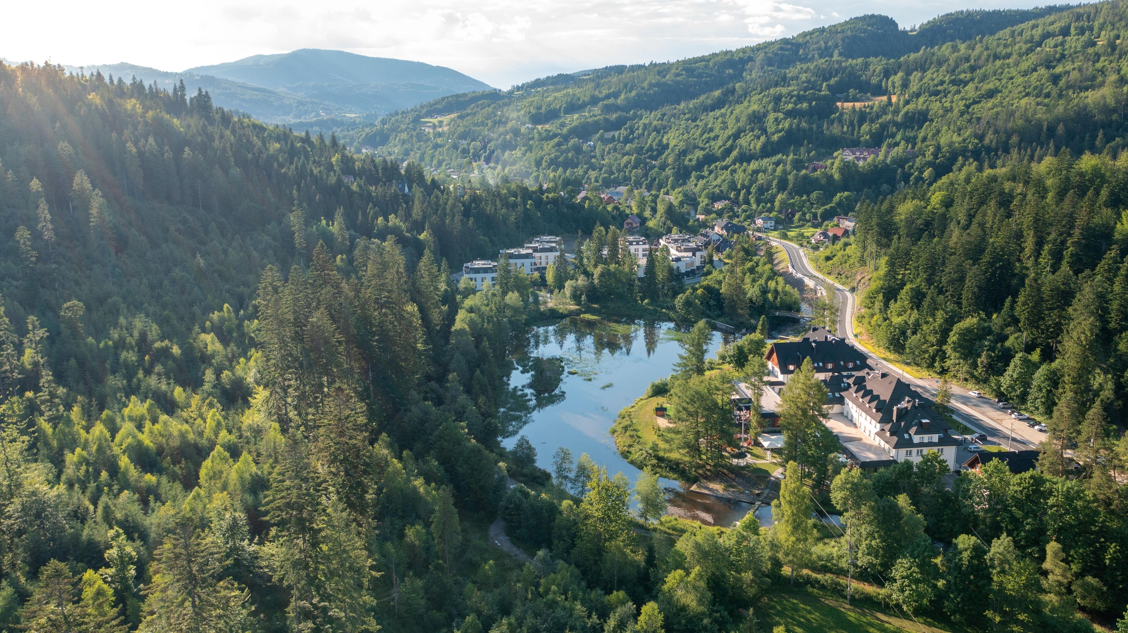 A riverside town with buildings along the water, surrounded by dense forest.
