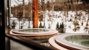 A hot tub area with a wooden pillar and a view of a snowy landscape. - Aries Hotel & SPA Wisla (Wisla)