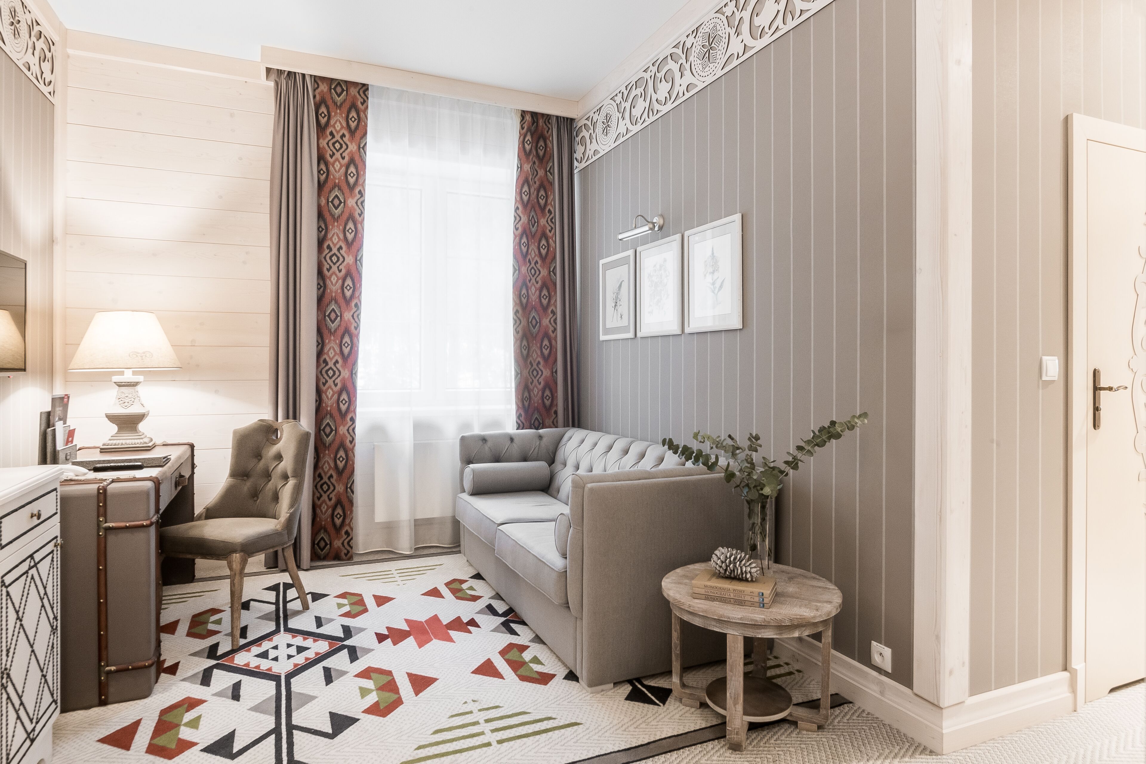 A modern living room with a sofa, armchair, and a small table with a vase.