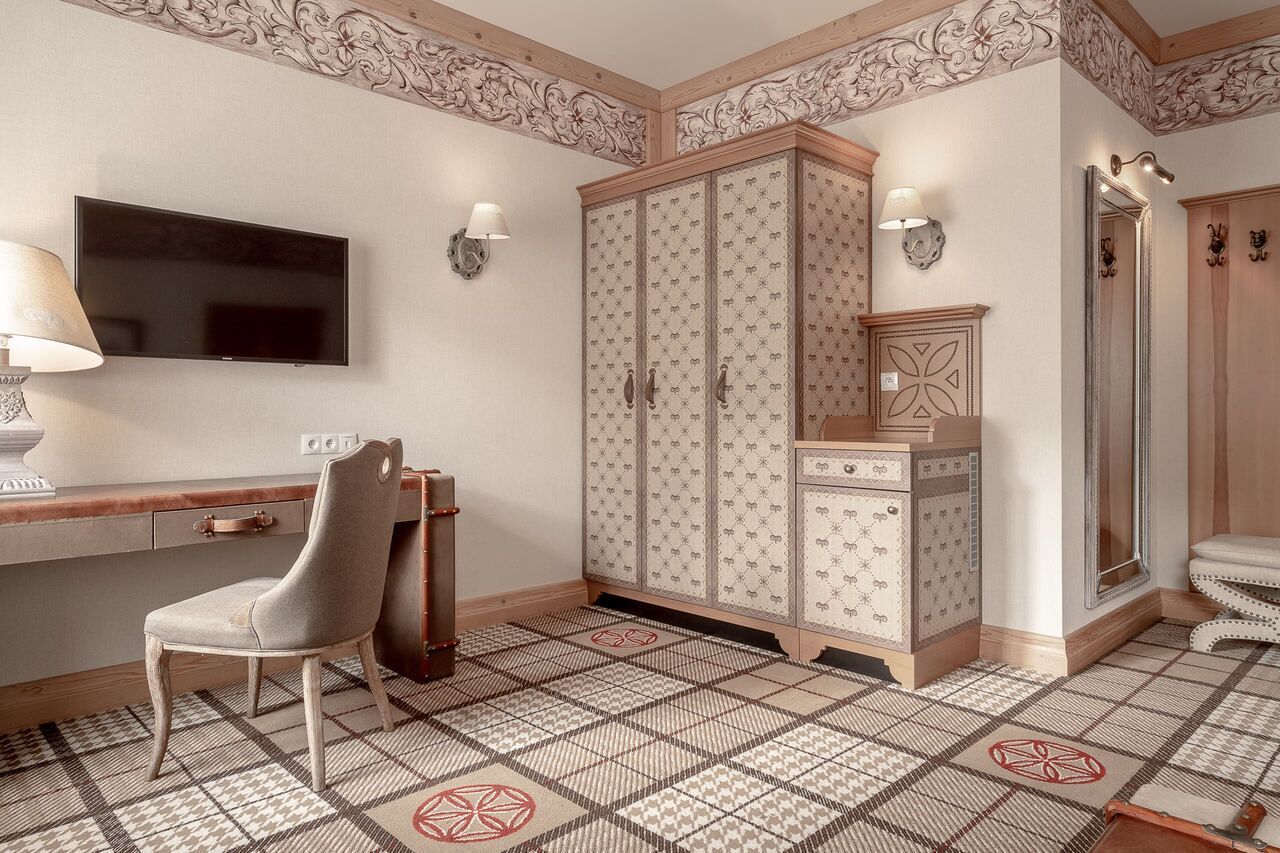 Habitación con televisión de pantalla plana, escritorio con silla, armario y espejo.
