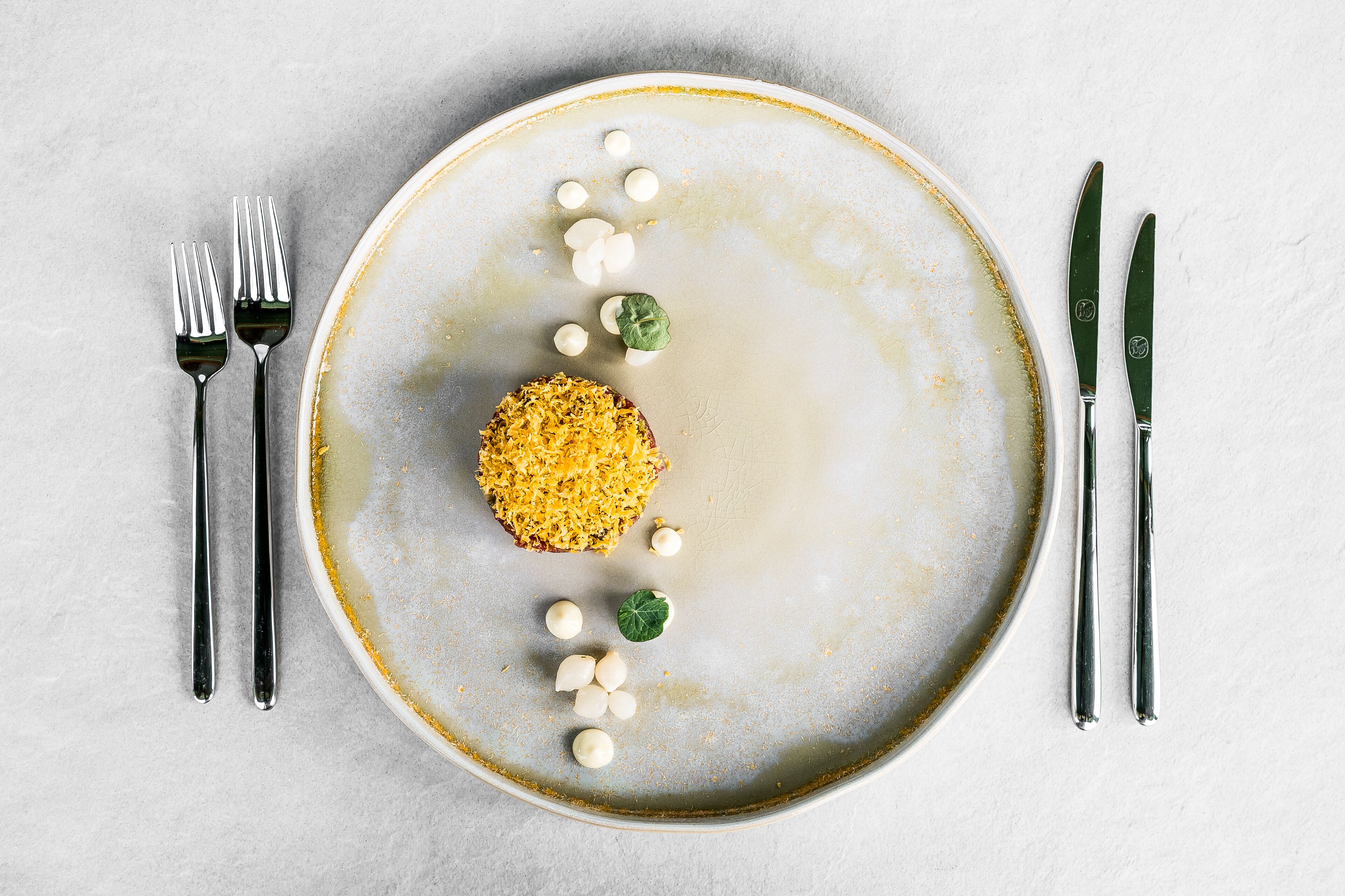 Une assiette contenant des aliments et des couverts, posée sur une surface texturée.