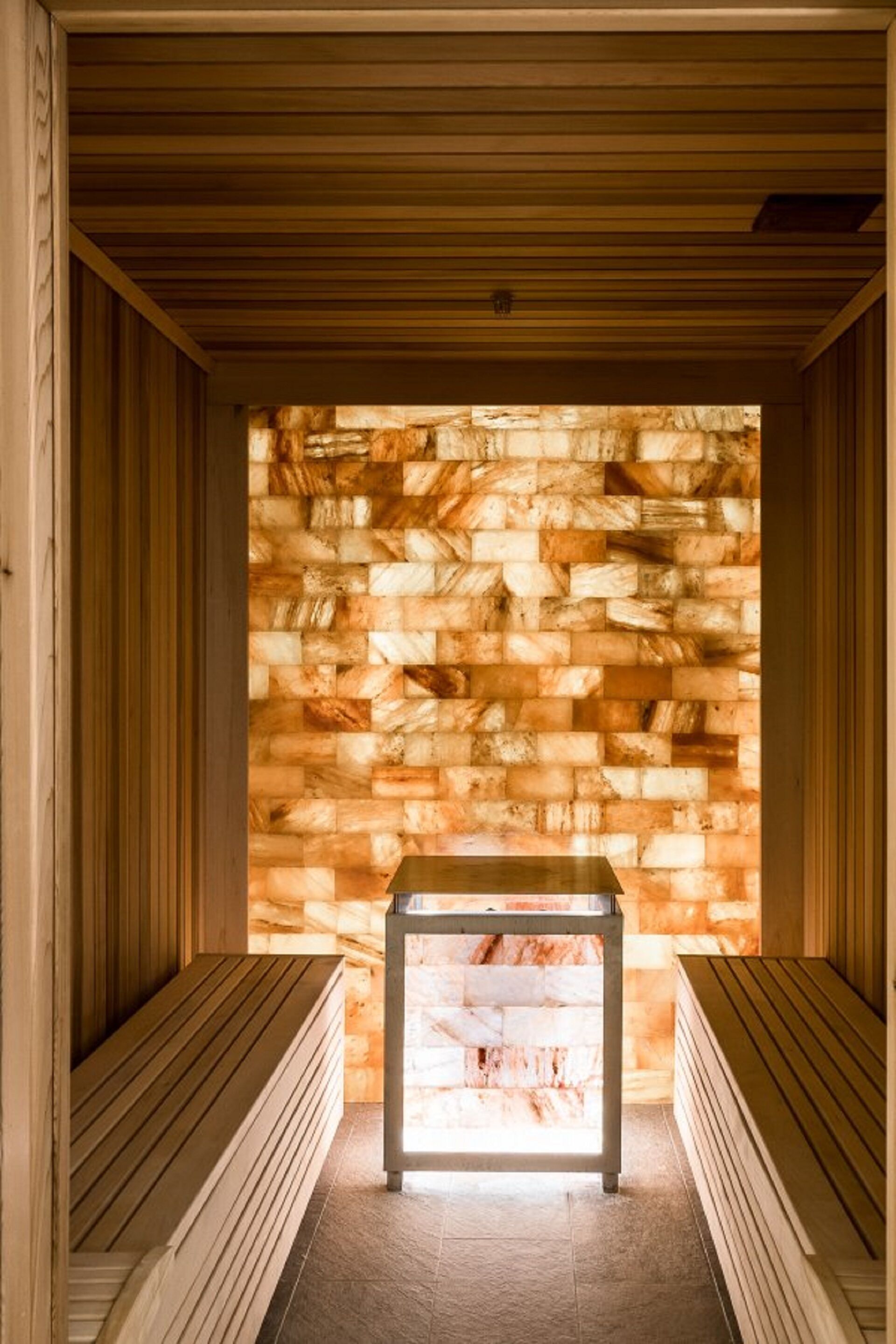 A sauna with wooden benches and a stone wall.