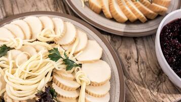 Ein Teller mit Brotscheiben und Pasta, garniert mit Petersilie, mit einer Schüssel dunklem Fruchtkompott im Hintergrund.