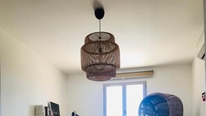 Uma sala de estar moderna com escrivaninha, poltrona, sofá e luminária suspensa.