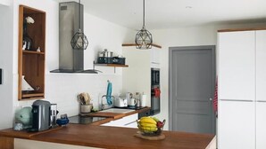 Uma cozinha moderna com ilha central, banquetas e iluminação pendente.