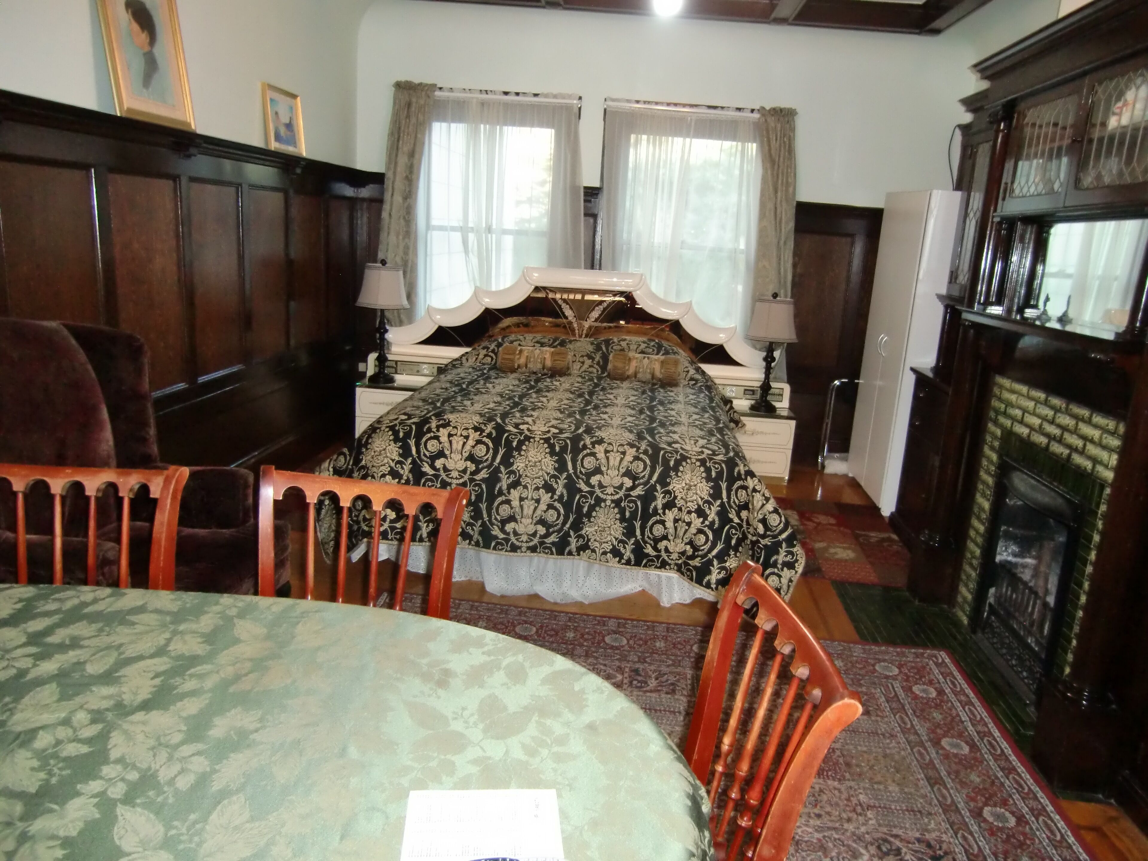 A traditional bedroom with a large bed, a fireplace, and a dining table.