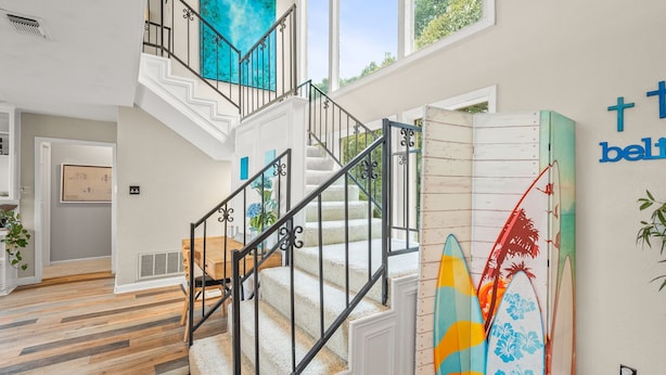 Un interior moderno con una escalera, una zona de comedor y tablas de surf en la pared.