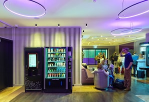 A modern lobby with a vending machine, seating area, and people waiting.
