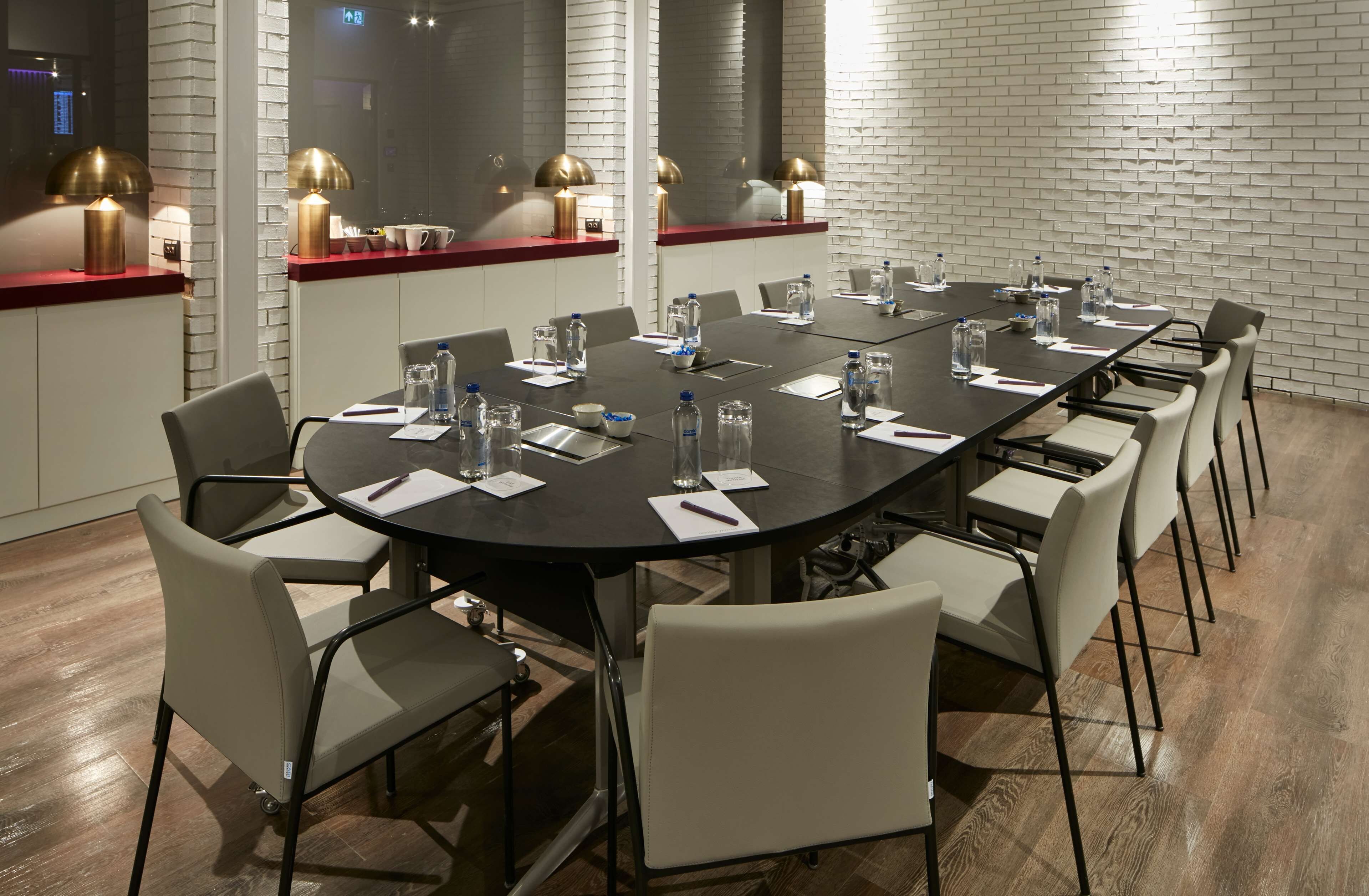 A conference room with a long table, chairs, water bottles, and documents.