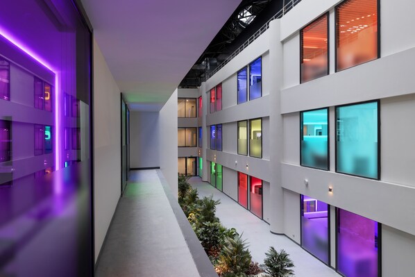 Ein modernes Gebäude mit mehreren Etagen, großen Fenstern und einer zentralen Halle mit Pflanzen.