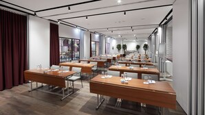 Une salle de conférence équipée de plusieurs tables, de chaises et d’une grande fenêtre.