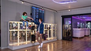 Un hall d’hôtel moderne doté d’un panneau d’affichage numérique, d’un comptoir de réception et d’une cloison en verre avec des chiffres rétroéclairés.