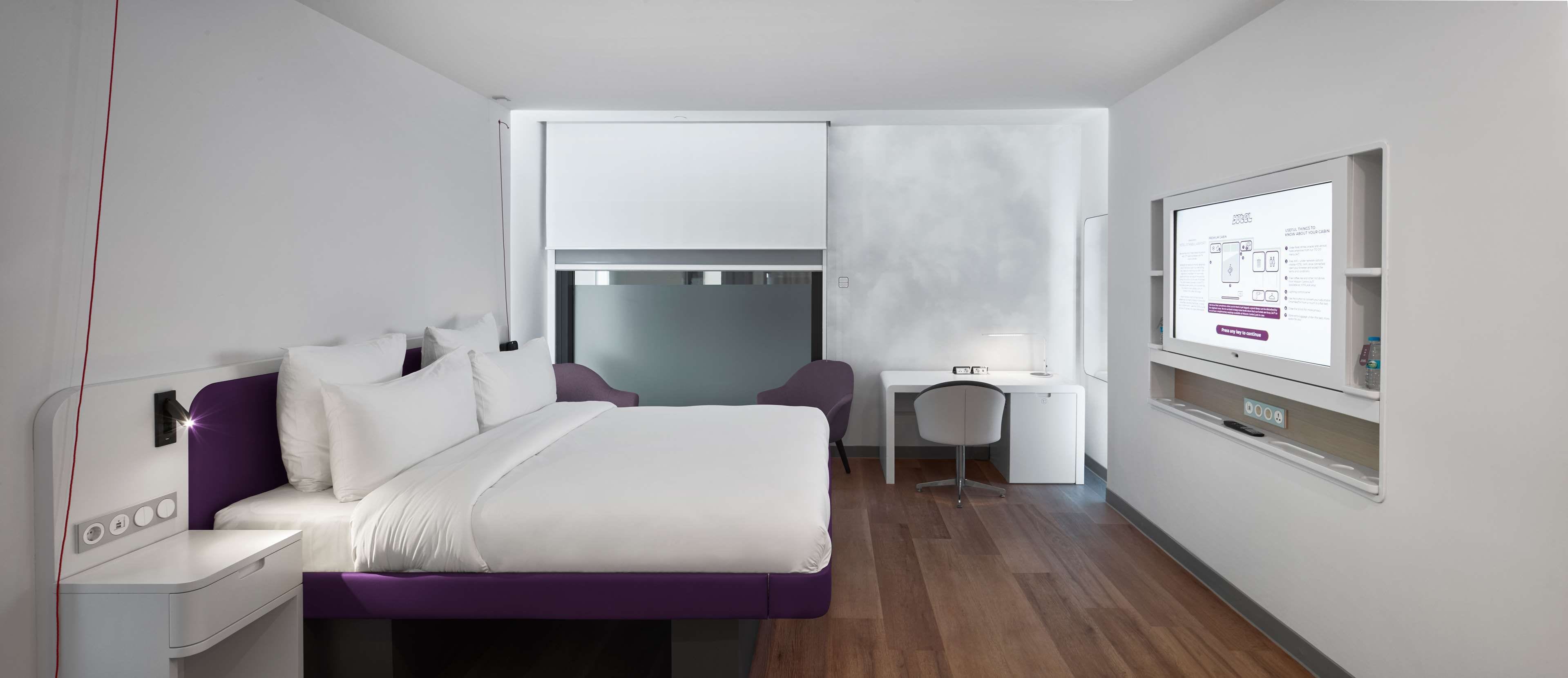 Una habitación de hotel moderna con una cama, un escritorio y una silla.