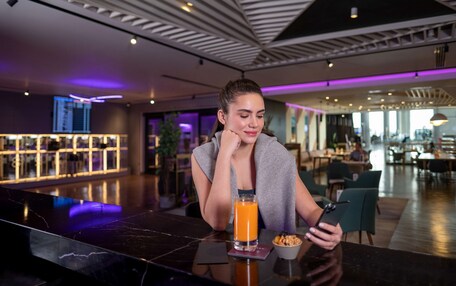 A modern interior with a marble bar, a glass of orange juice, and a person using a smartphone.